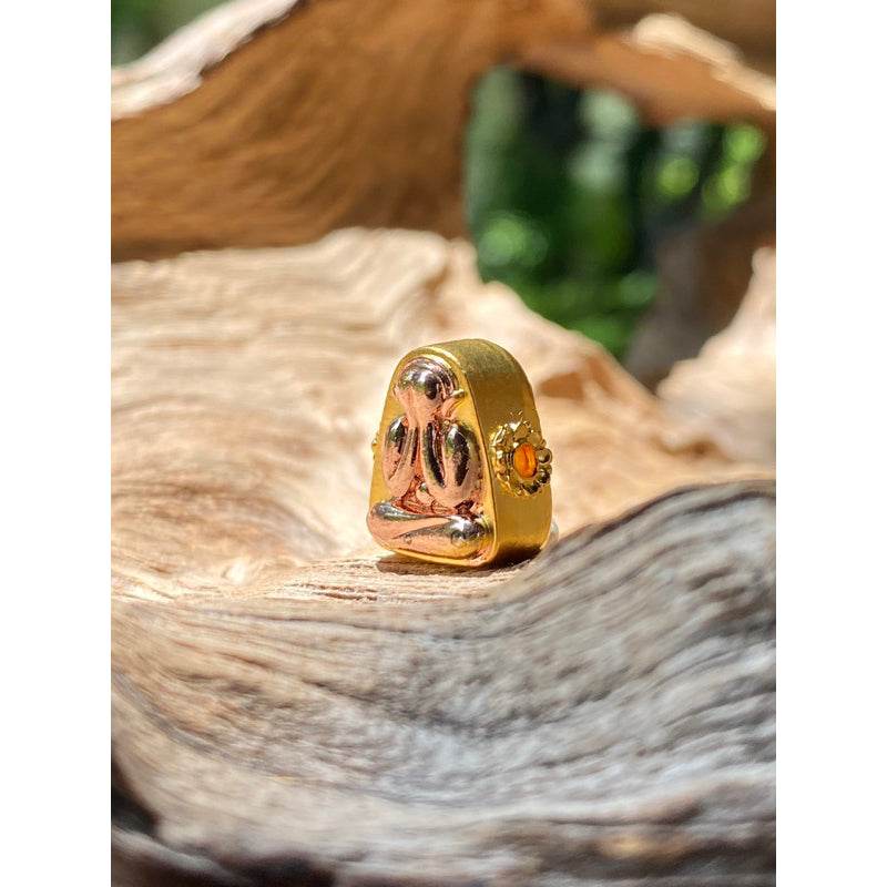 Phra Pidta amulet for sale gold metal covered amulet with orange gem set in decorative casing on wood