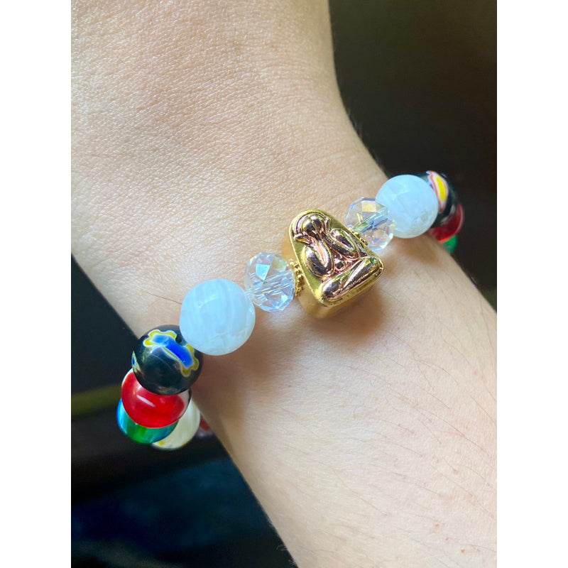 Gold Phra Pidta amulet for sale on multicolor beaded bracelet with white crystal beads on wrist