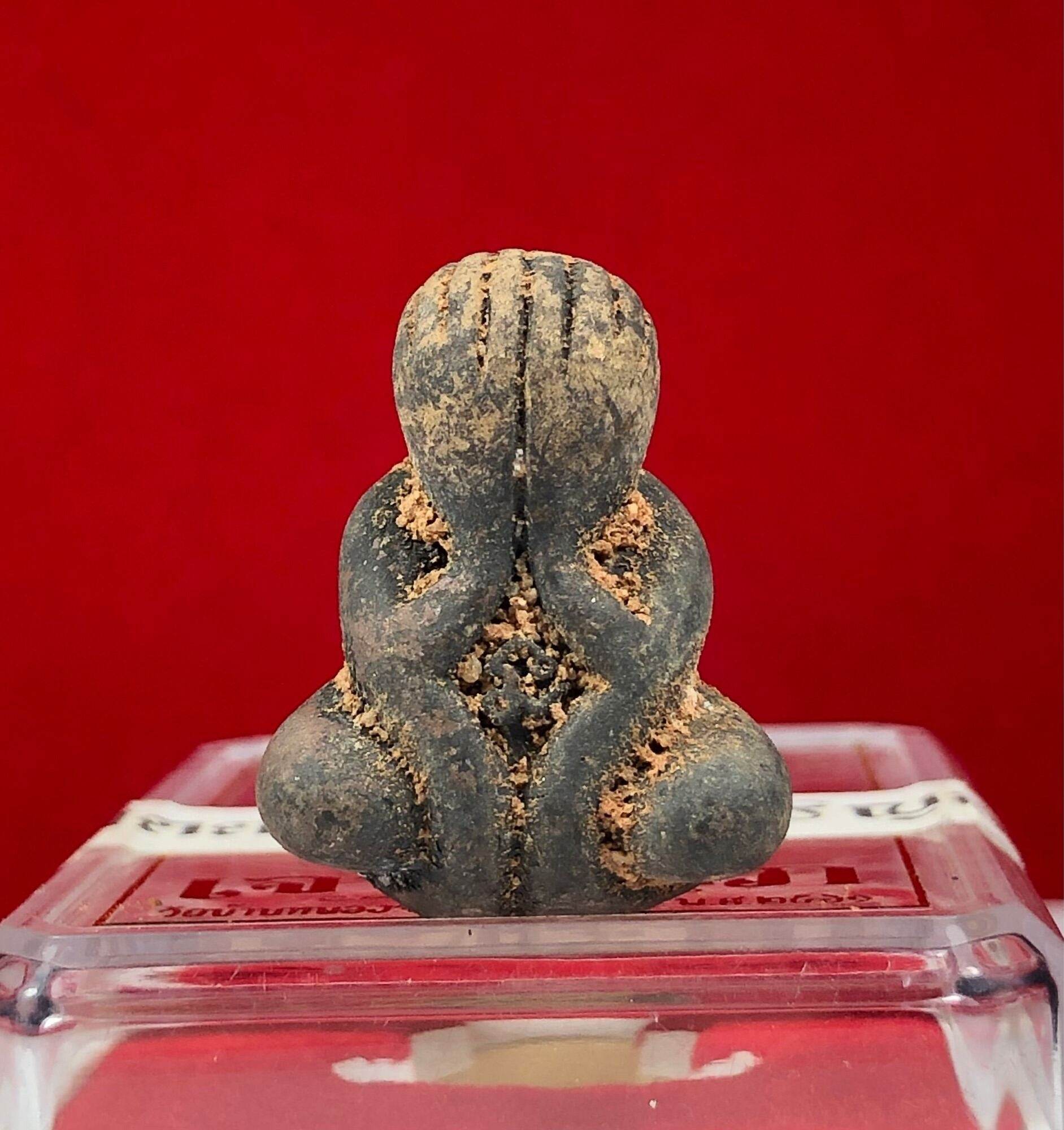 Phra Pidta Ancient Amulet small seated clay amulet figure covering face aged patina on clear display stand