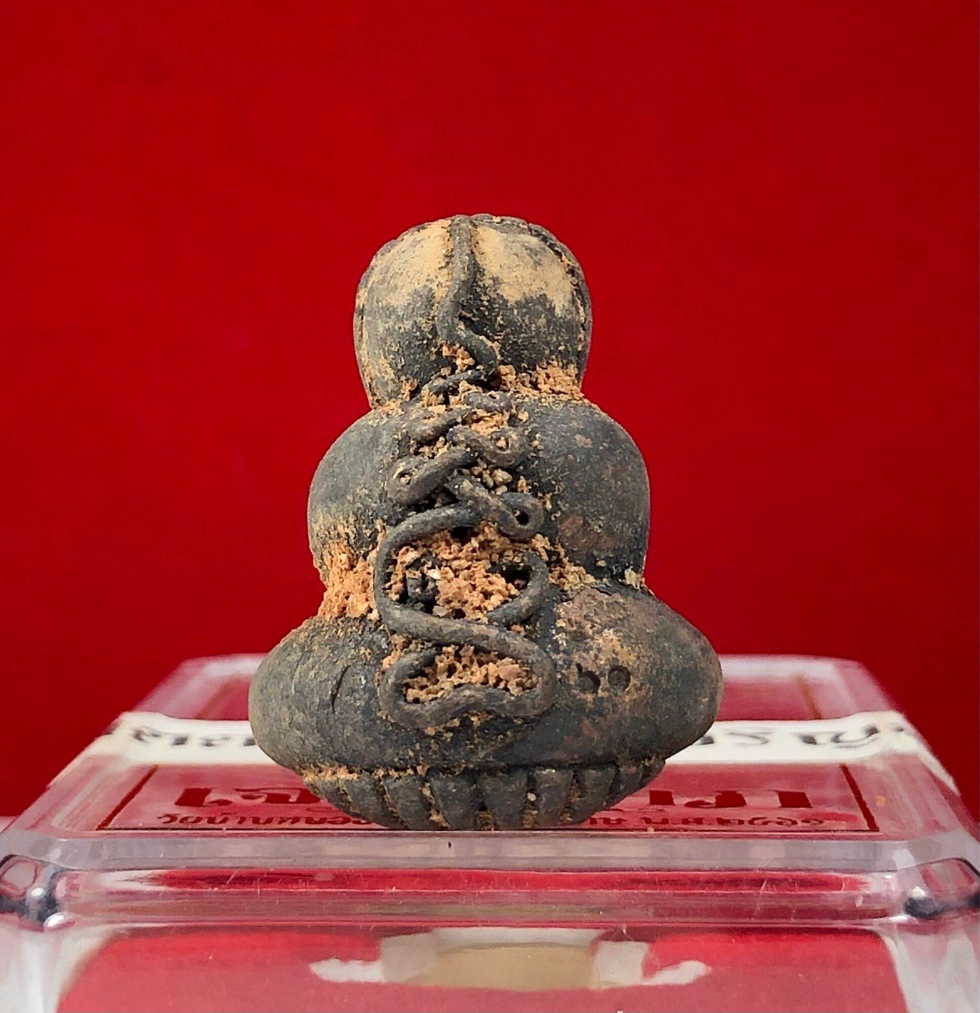 Phra Pidta Ancient Amulet weathered seated clay pendant with soil encrustation on clear stand