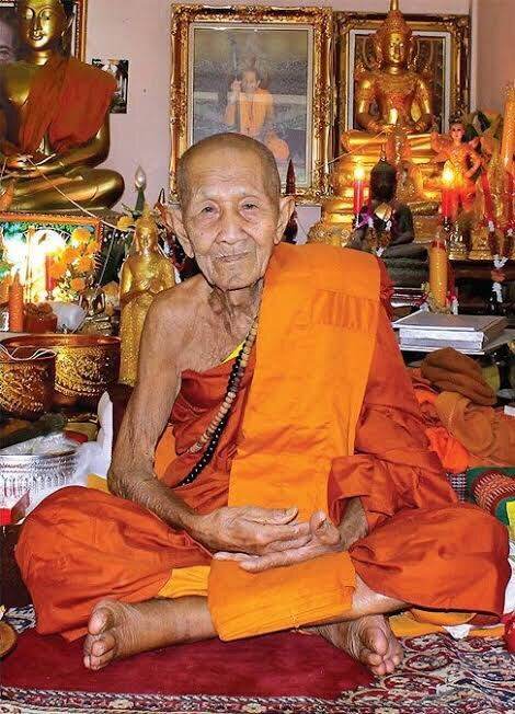 Phra Pidta Ancient Amulet pendant with elderly Buddhist monk in orange robes seated in temple shrine