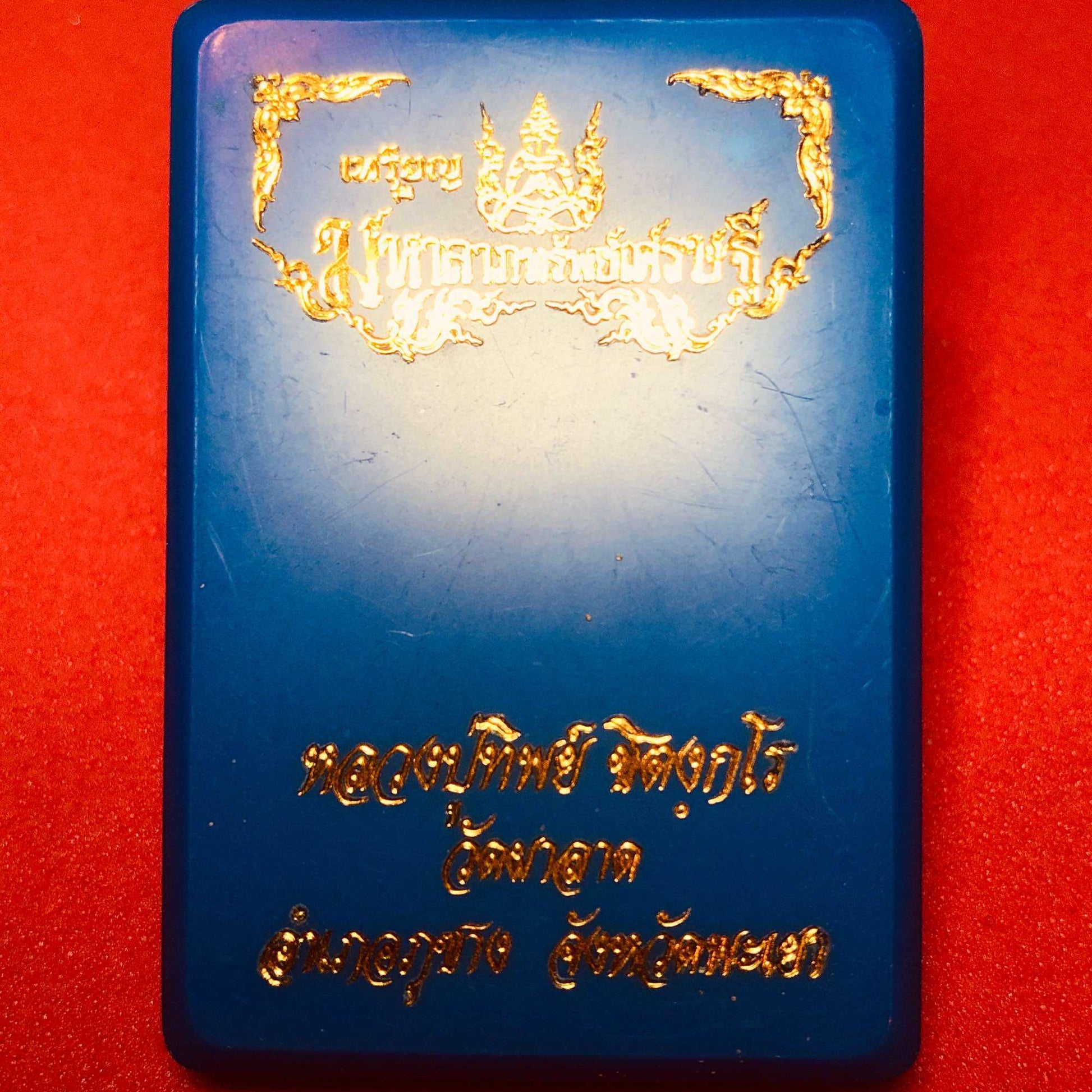 Blue amulet case with gold Thai script by Thai Blessing Co containing Phra Pidta Maha Lap amulet for wealth