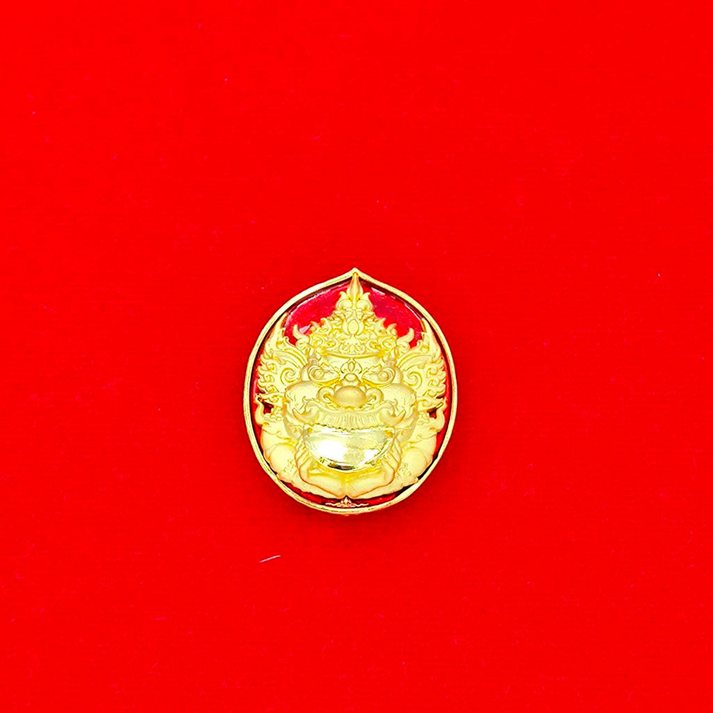 Gold Rahu deity amulet with ornate Thai guardian face on red background decorative collectible
