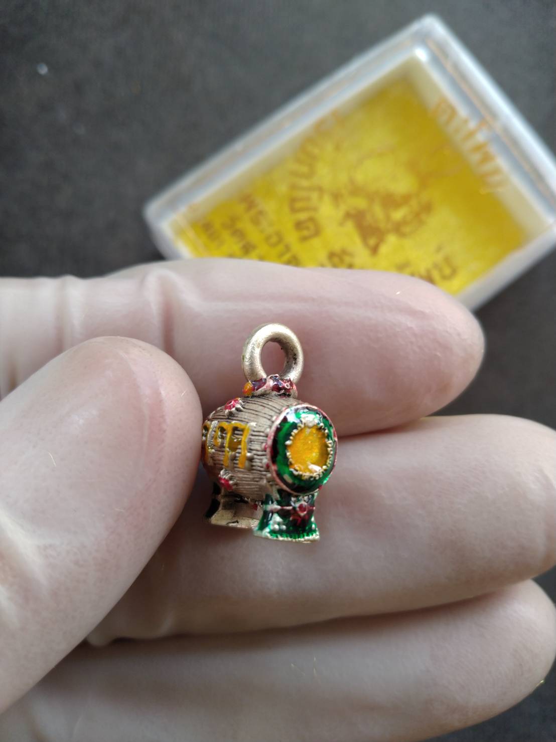 Thai Blessing Co small gold enamel Sacred Drum Amulet for Wealth Prosperity Blessed by Phra Ajarn Tao. held in hand