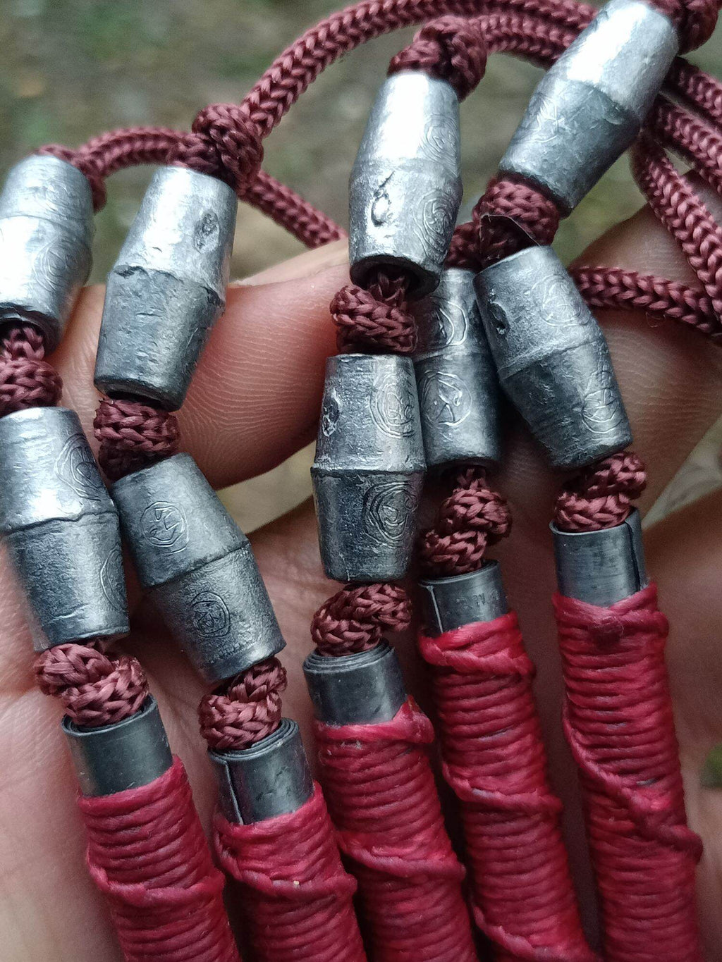 Close up of multiple Sacred Thai takrut blessed by Luang Pho Pleung on brown cords with red wraps