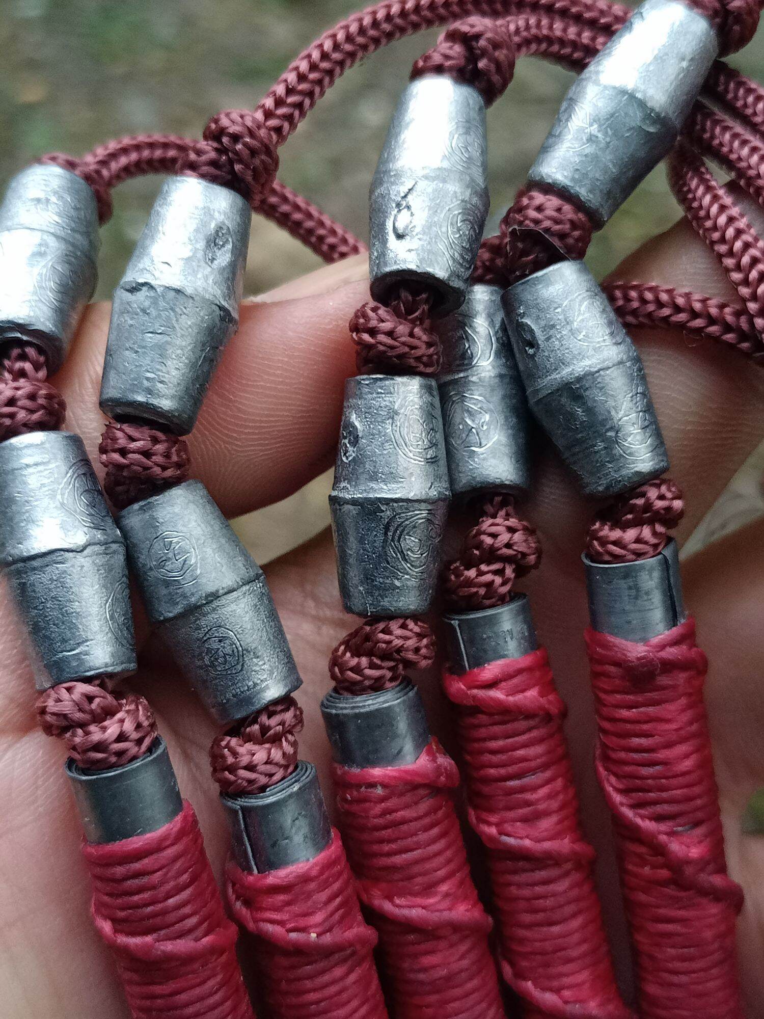 Close up of multiple Sacred Thai takrut blessed by Luang Pho Pleung on brown cords with red wraps