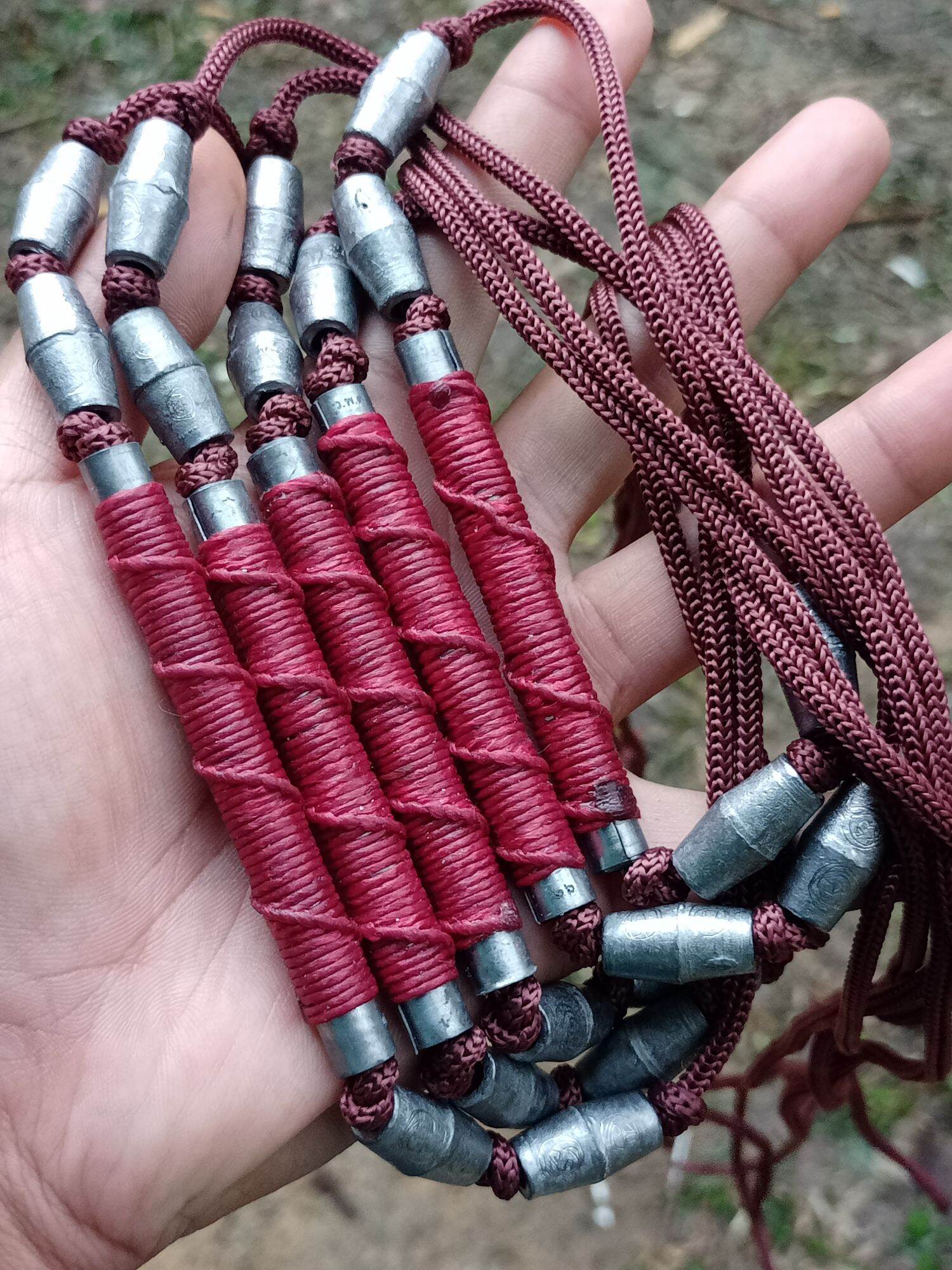 Sacred Thai takrut blessed by Luang Pho Pleung red wrapped metal tube amulet pendants on brown cords