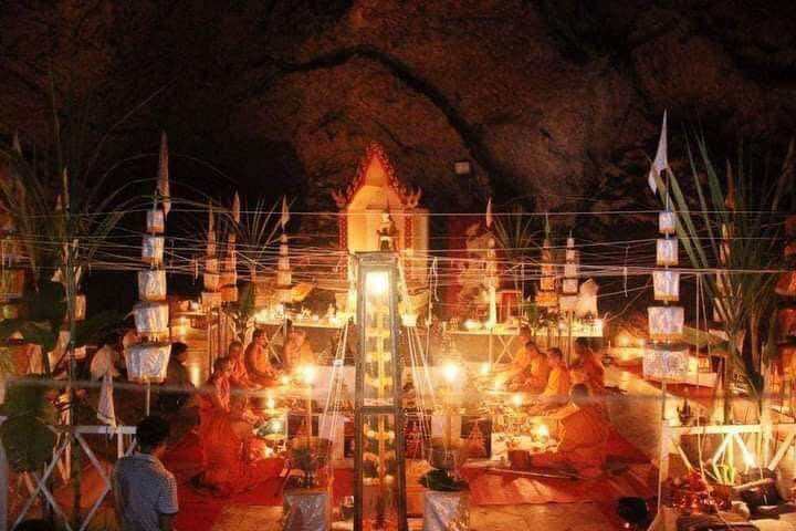 Takrut Jan Pen Full Moon Phayak Taksila ceremony with monks lighting candles around shrine in cave