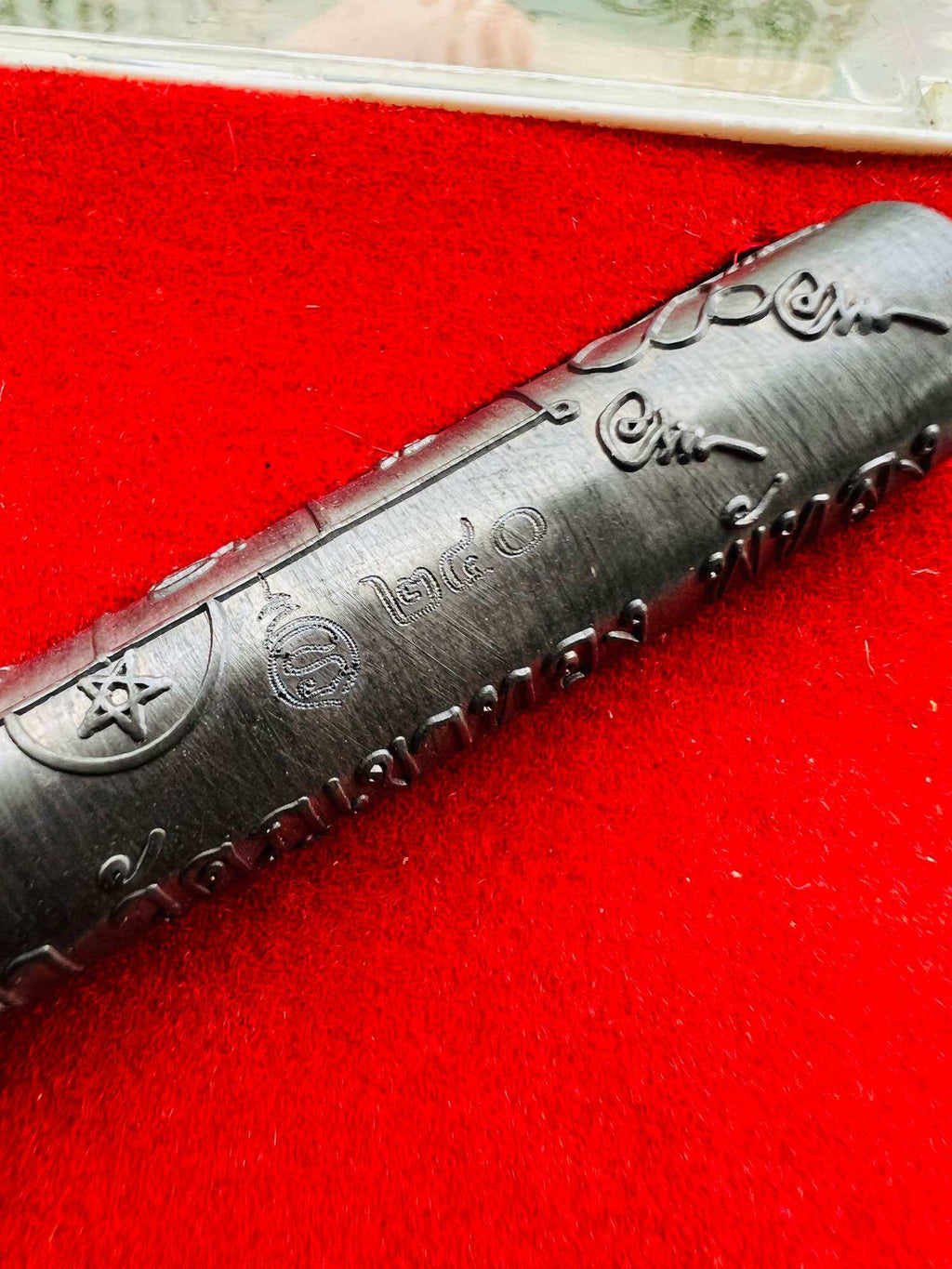 Takrut Jan Pen Full Moon Phayak Taksila black engraved amulet cylinder on red velvet background Thai Blessing Co