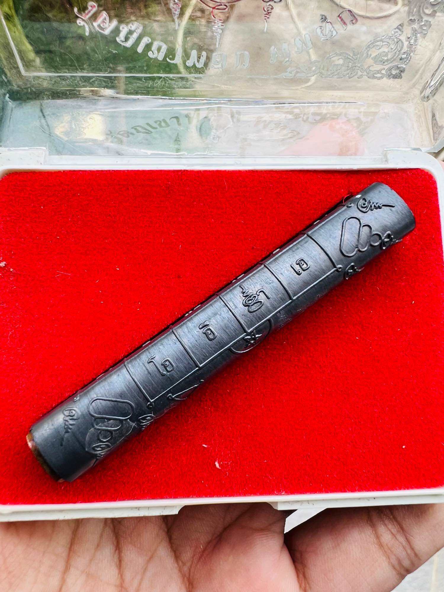 Thai Blessing Co Takrut amulet cylinder on red velvet tray engraved with yantra script Takrut Jan Pen Full Moon Phayak Taksila