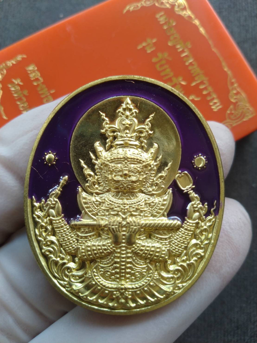 Thai Blessing Co Thao Wessuwan amulet blessed by Luang Pho Phat. Gold oval medallion with purple enamel detailed deity held