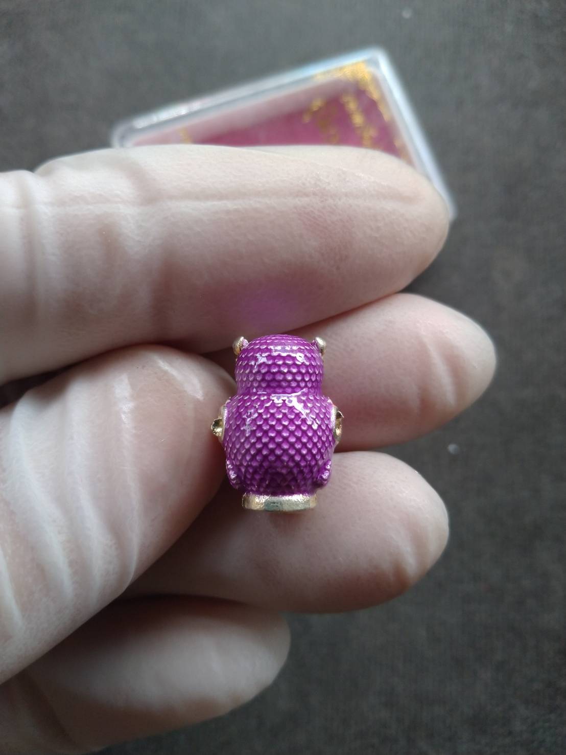 Thep Rattikan oom sap amulet purple enameled textured pendant with gold trim held in gloved hand