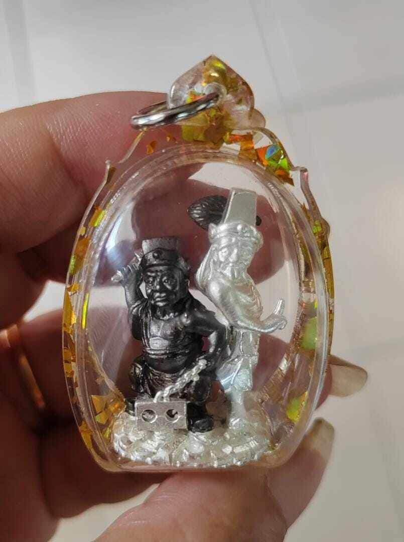 Tua Pae-Yee Pae Amulet - 2 Deities of Wealth clear resin amulet case with silver and black deity figures held in hand