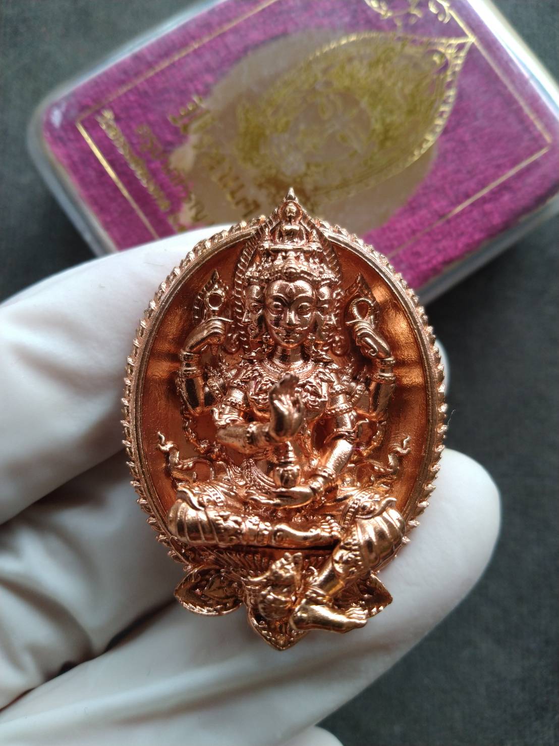Copper Wat Thammachai Mongkhon Brahma talisman pendant with detailed deity carving held in gloved hand