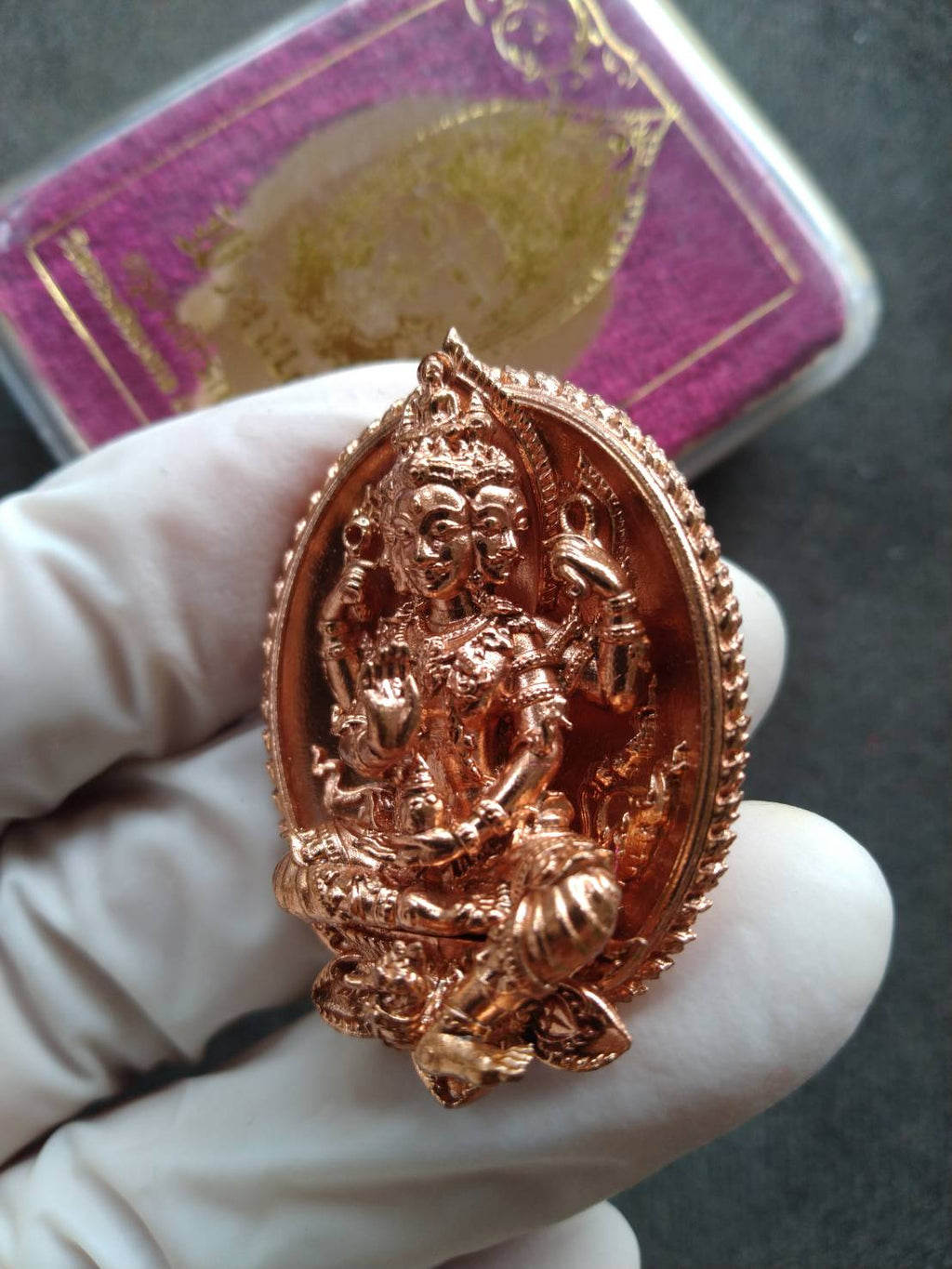 Wat Thammachai Mongkhon Brahma talisman copper pendant detailed Thai blessing amulet held in gloved hand