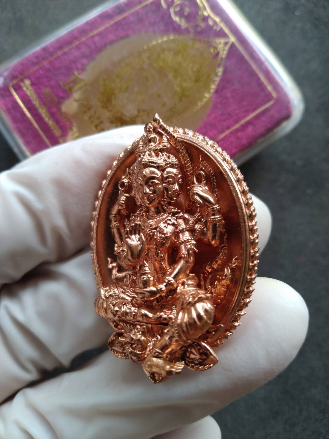 Wat Thammachai Mongkhon Brahma talisman copper pendant detailed Thai blessing amulet held in gloved hand