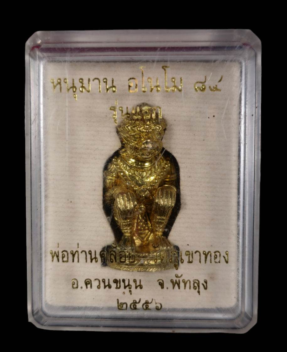 Gold seated Hanuman figurine in clear display case with Thai script background authentic Thai Hanuman amulet