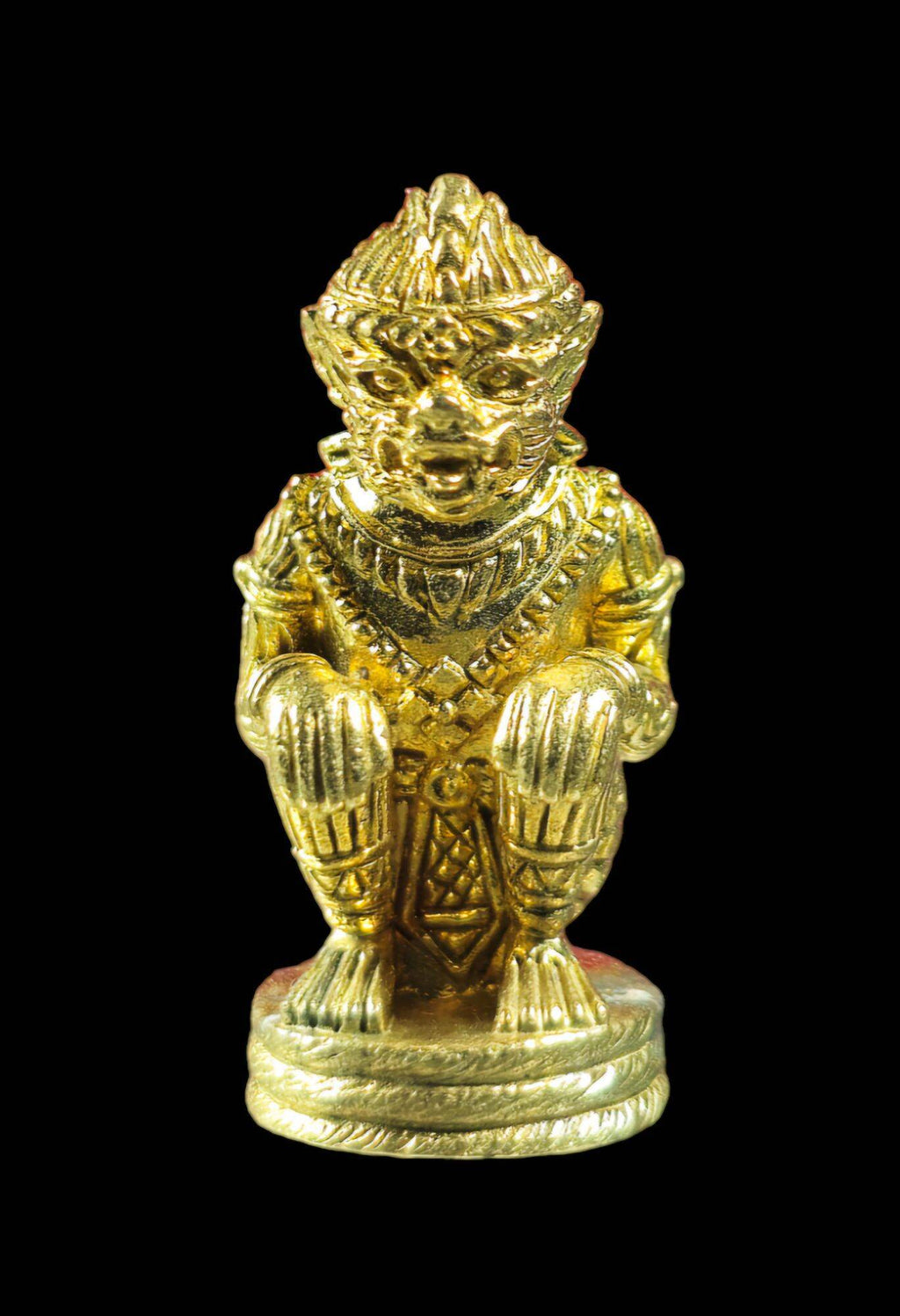 Gold metal figurine of Hanuman on a pedestal in squatting pose with ornate detailing authentic Thai Hanuman amulet for collectors
