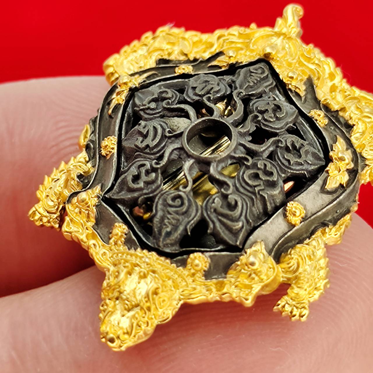 Kassapo Turtle wealth amulet ornate gold plated turtle talisman with black carved center held on fingers