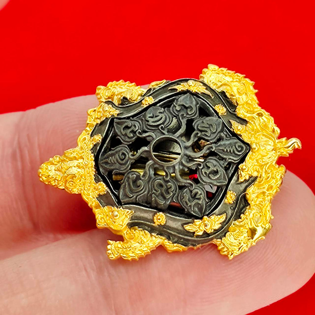 Kassapo Turtle wealth amulet ornate gold and black turtle amulet with intricate carvings held on fingertip
