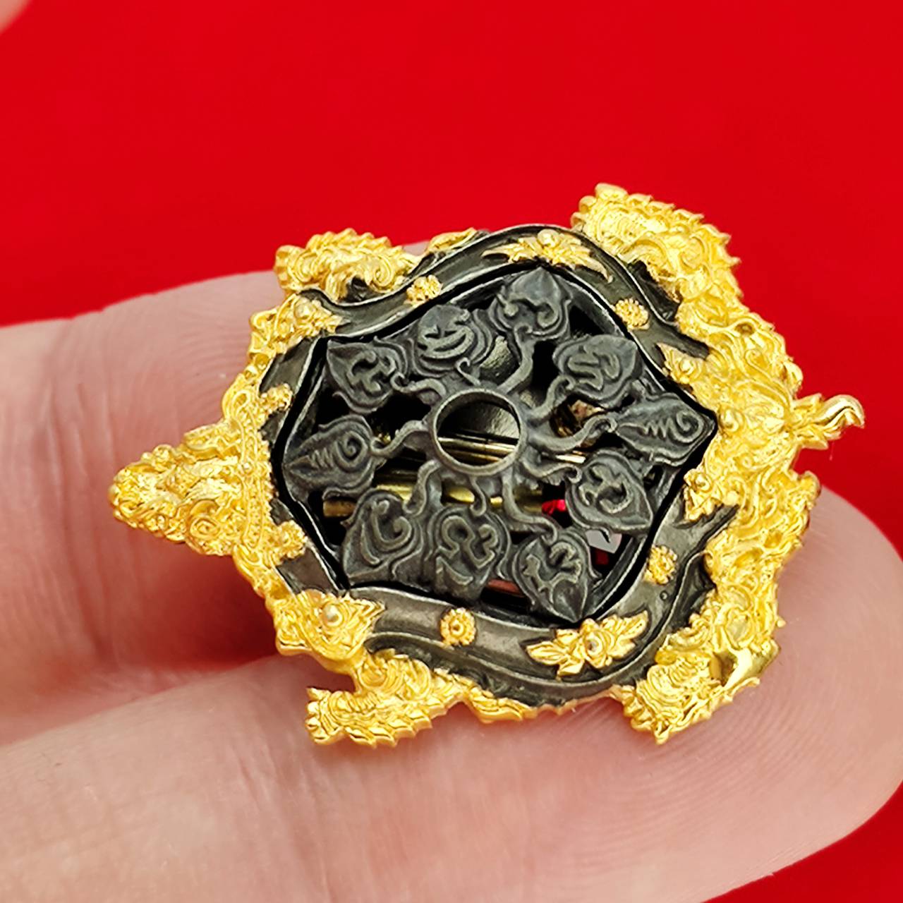 Kassapo Turtle wealth amulet ornate gold and black turtle amulet with intricate carvings held on fingertip