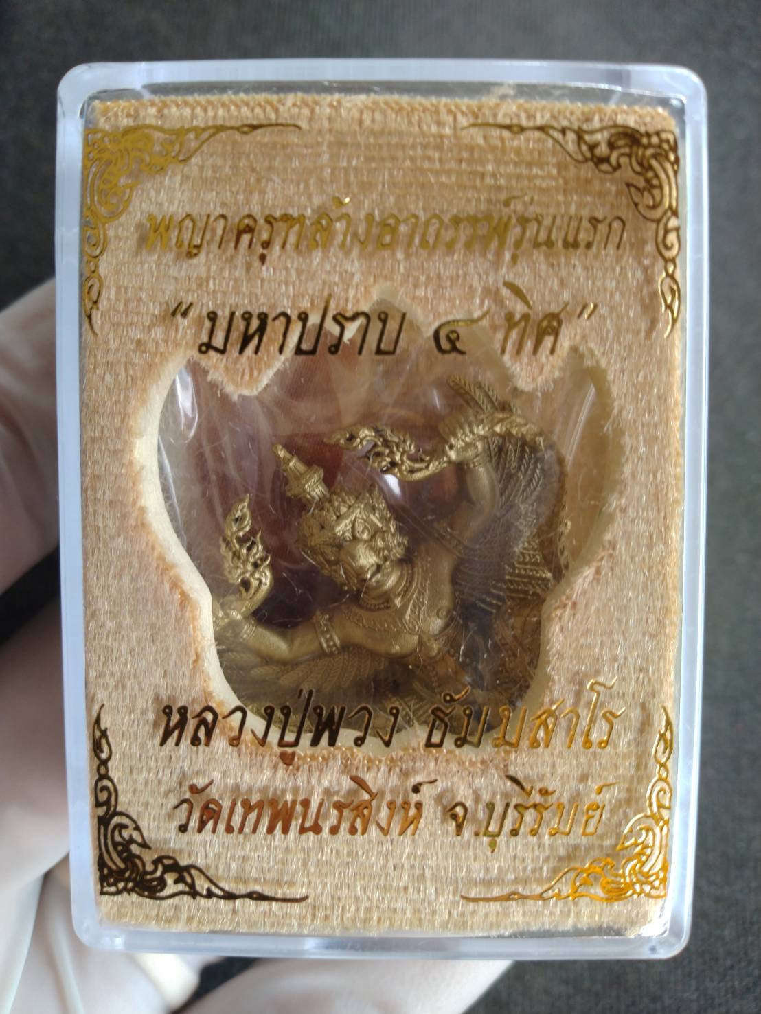 Thai gold tone Phaya Krut Garuda Amulet . Encased in clear plastic case with printed Thai blessing card