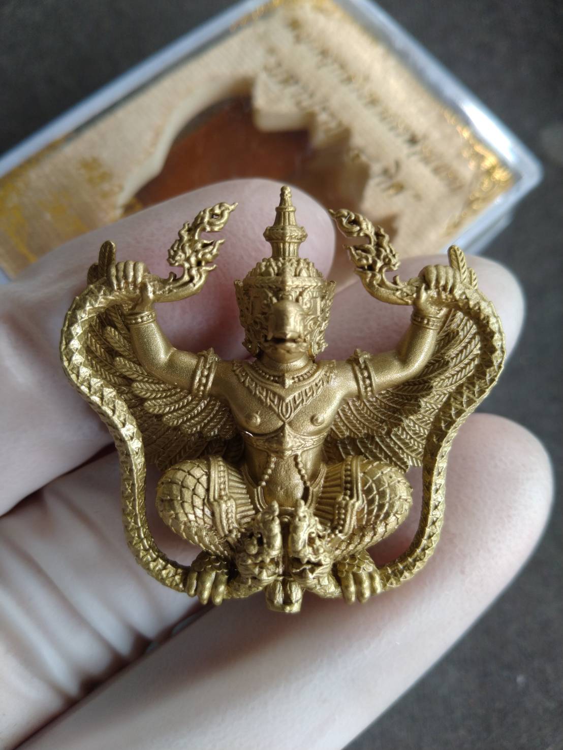 Phaya Krut Garuda Amulet gold pendant by Thai Blessing Co shown in a gloved hand with intricate wings and carving