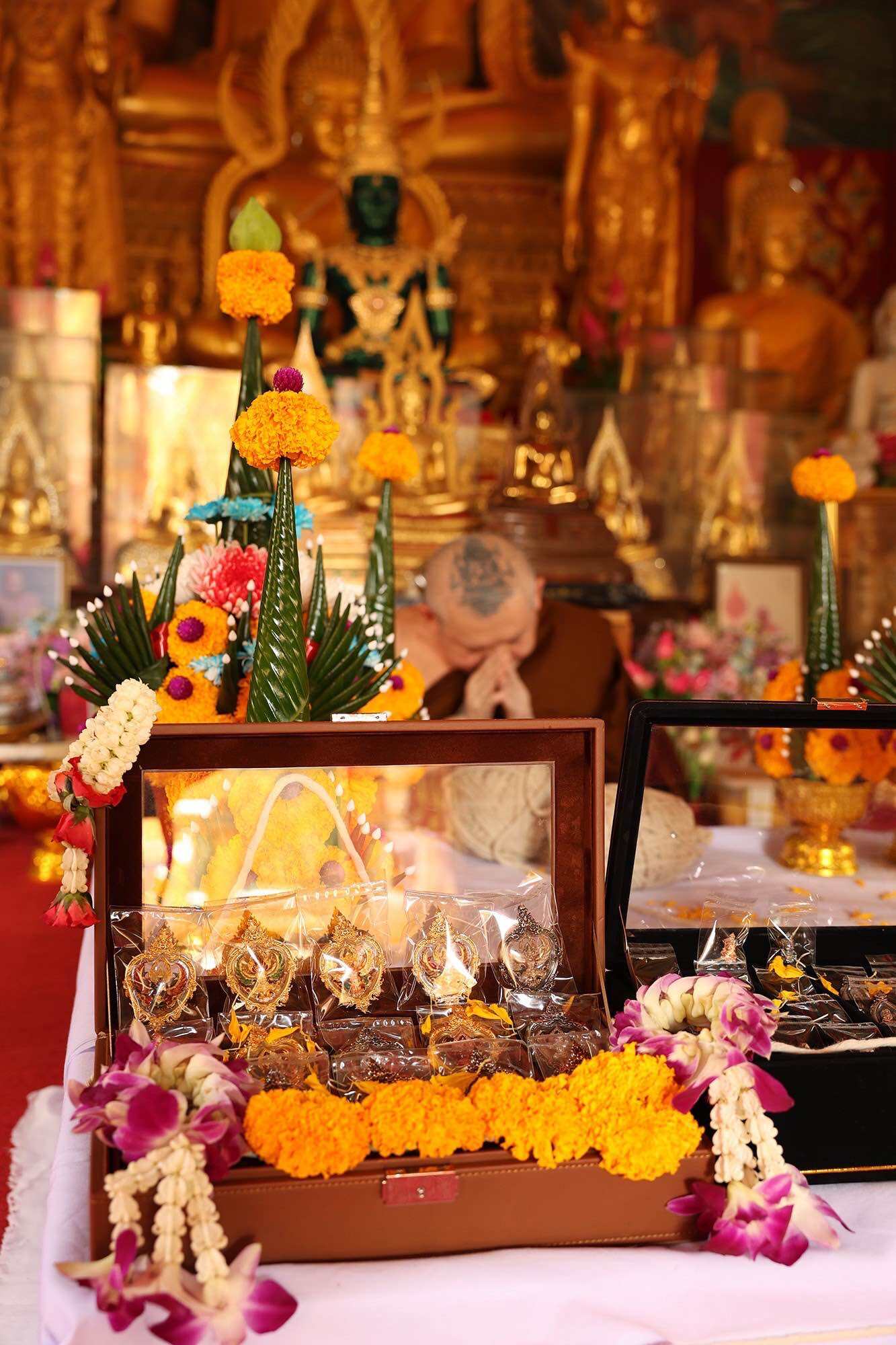 Thai Garuda car display amulet set in wooden box with marigold and orchid garlands at temple