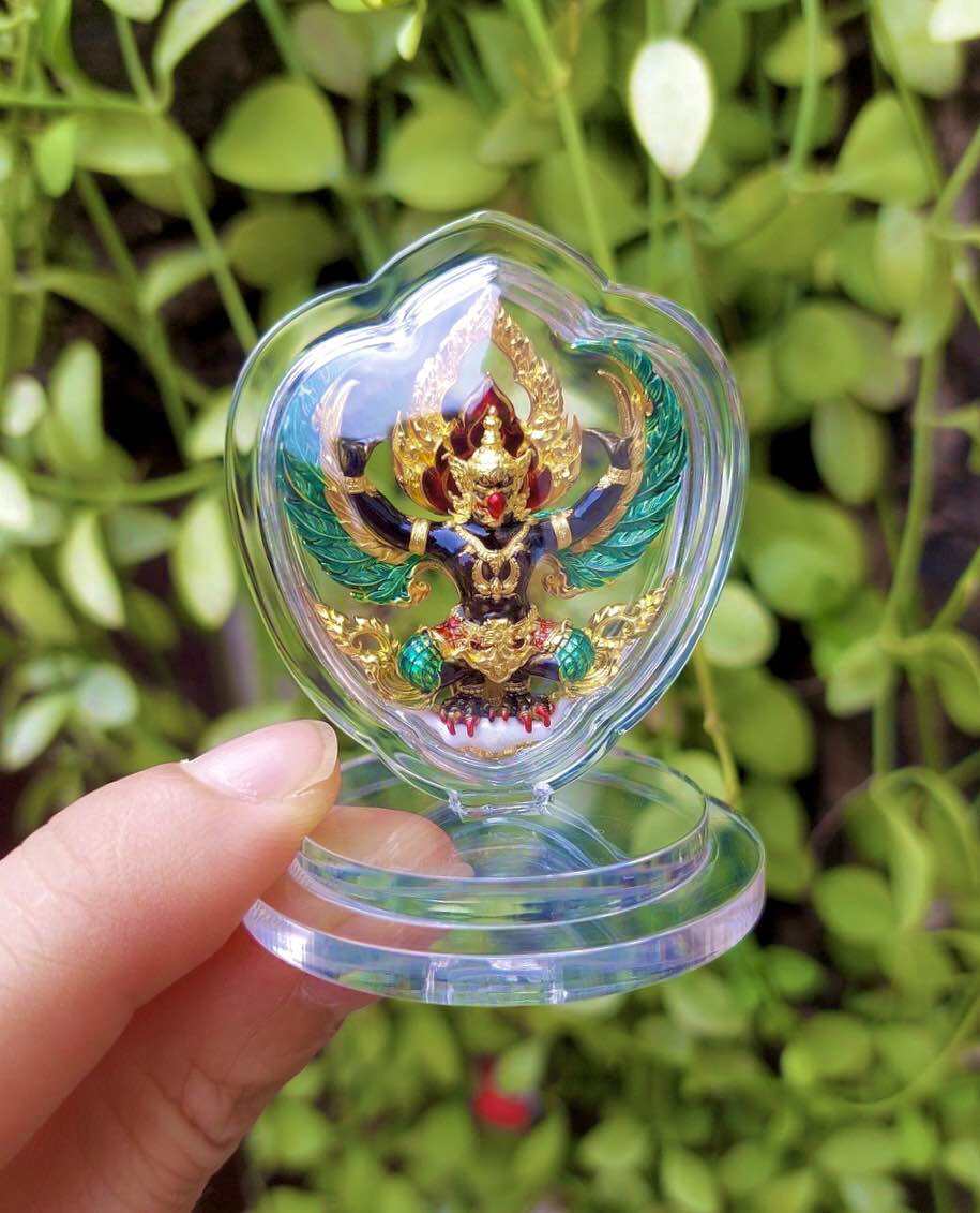 Handheld clear acrylic heart display with gold and green Thai Garuda car display amulet on pedestal base