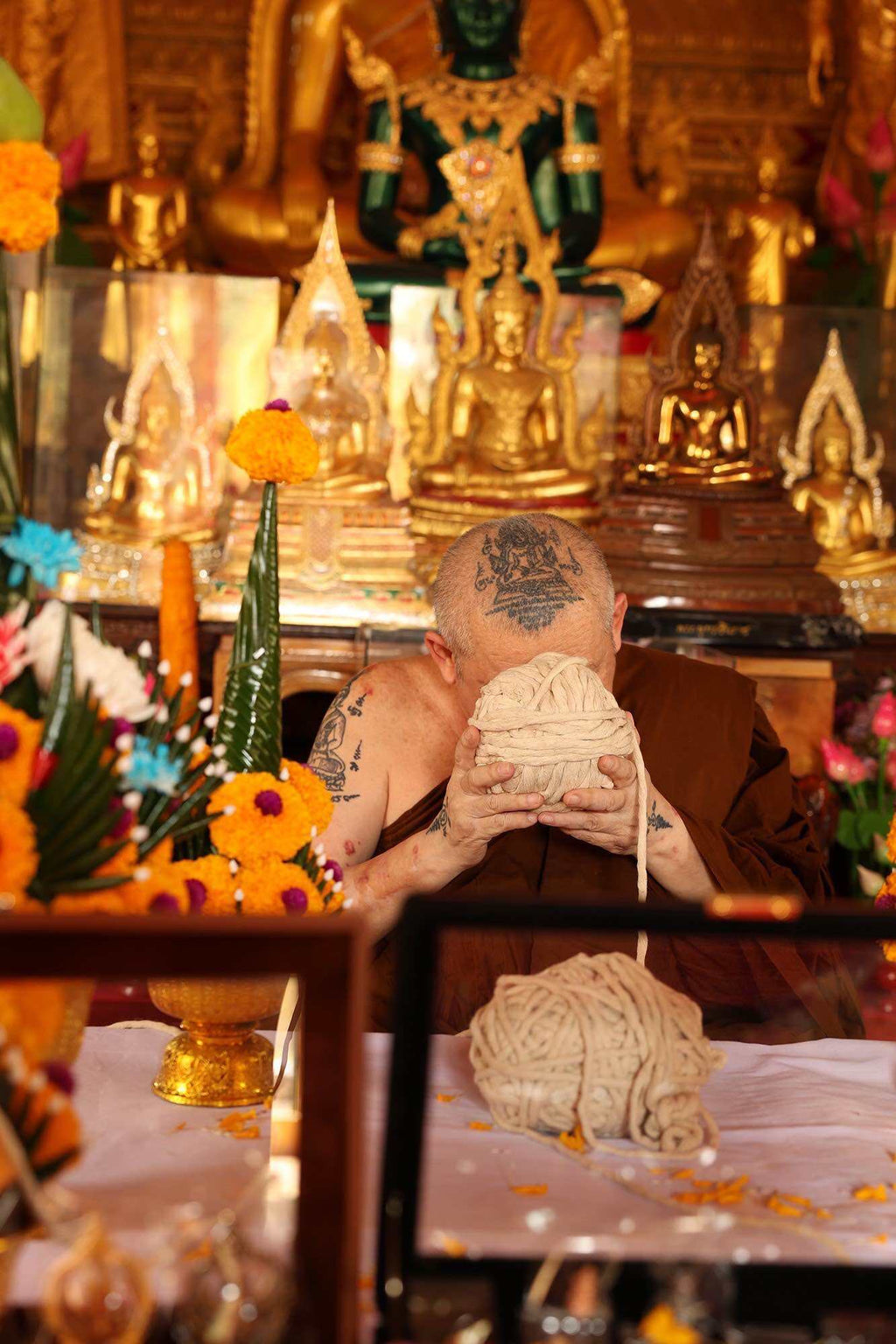 Thai Garuda car display amulet displayed at temple altar held by monk among Buddha statues and offerings