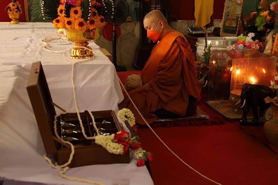 Thai monk with Thao Wessuwan amulet for protection during a ceremonial blessing in a temple.