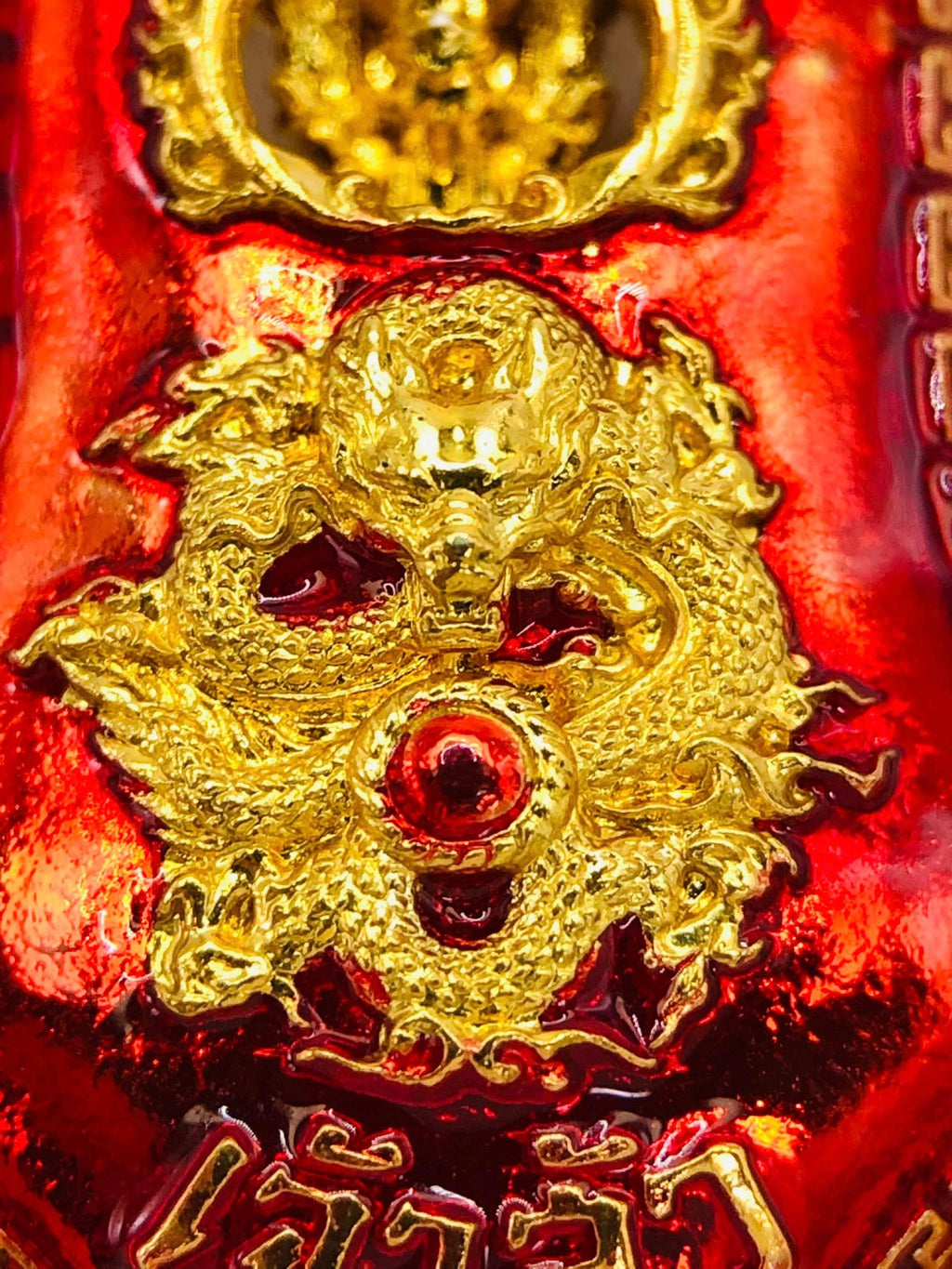 Close-up of Thao Wessuwan amulet for sale featuring intricate gold dragon design on a vibrant red background