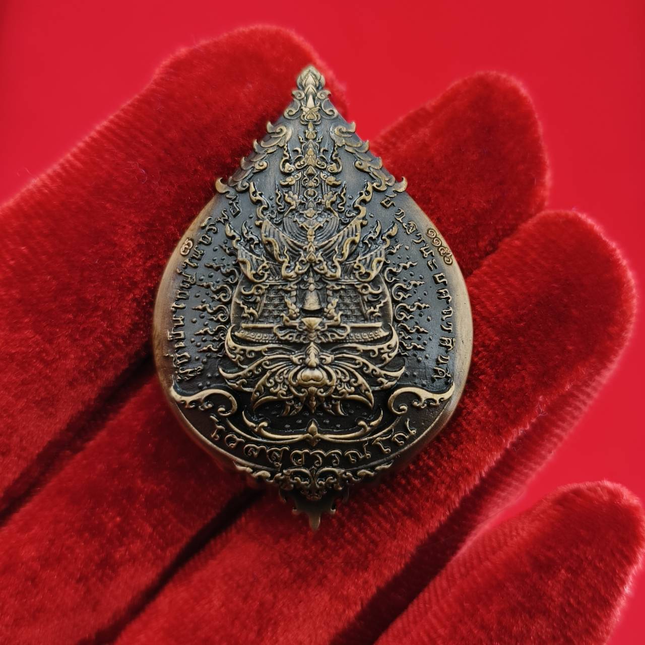 Thao Wessuwan amulet for wealth with intricate design on a decorative red background