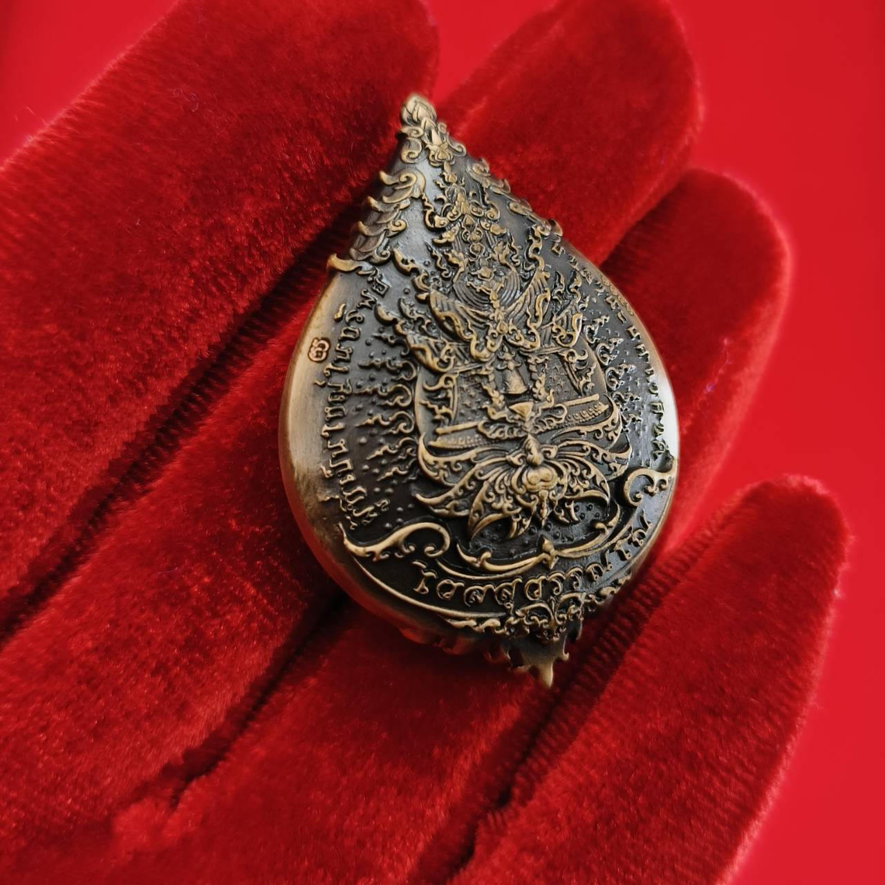Thao Wessuwan amulet for wealth with intricate design displayed on a red velvet background
