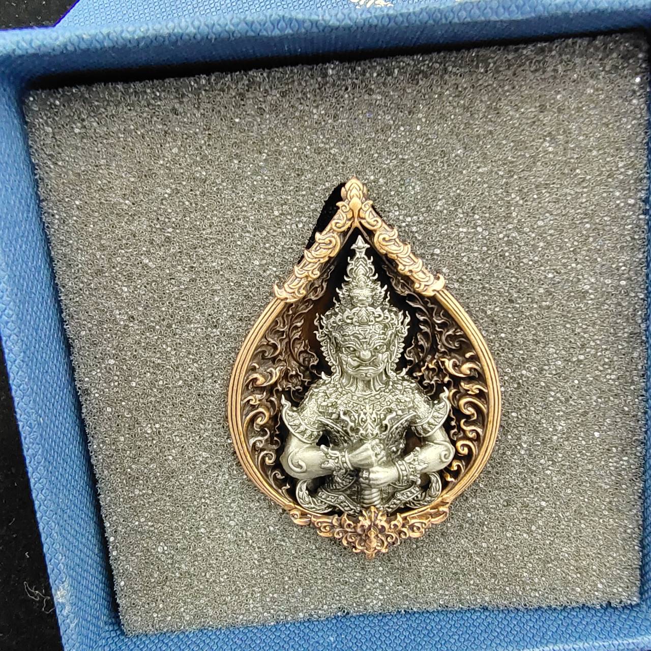 Thao Wessuwan amulet for wealth in an ornate gold and silver design displayed in a blue box