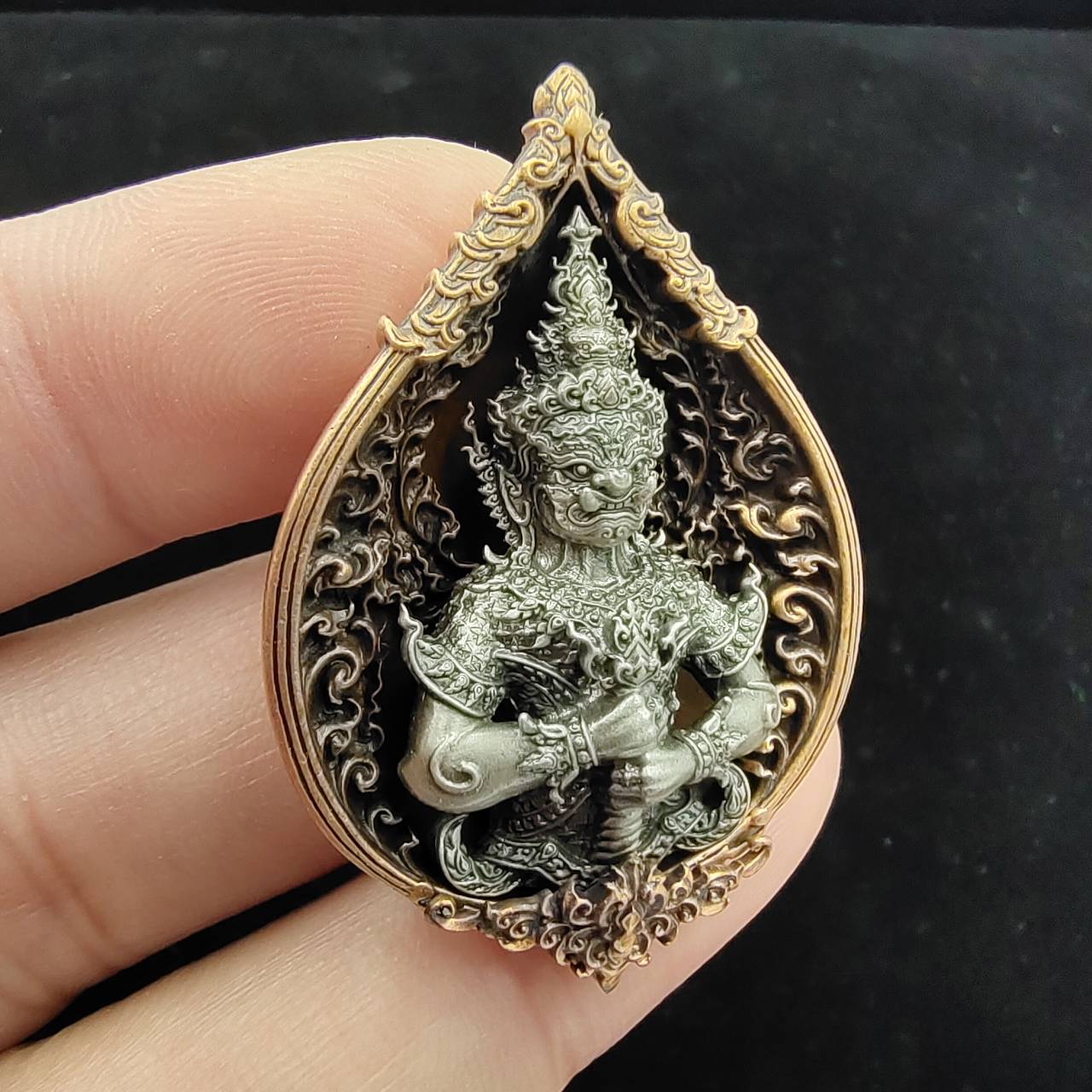 Thao Wessuwan amulet for wealth in decorative resin with intricate detailing held by hand