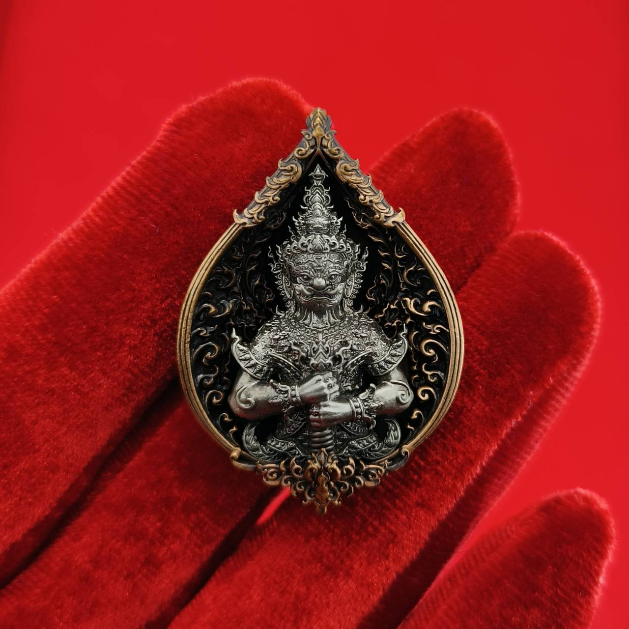 Thao Wessuwan amulet for wealth displayed on red velvet, intricately designed with detailed craftsmanship