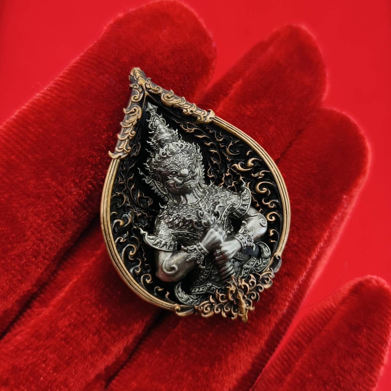 Thao Wessuwan amulet for wealth displayed on a plush red background with intricate detailing