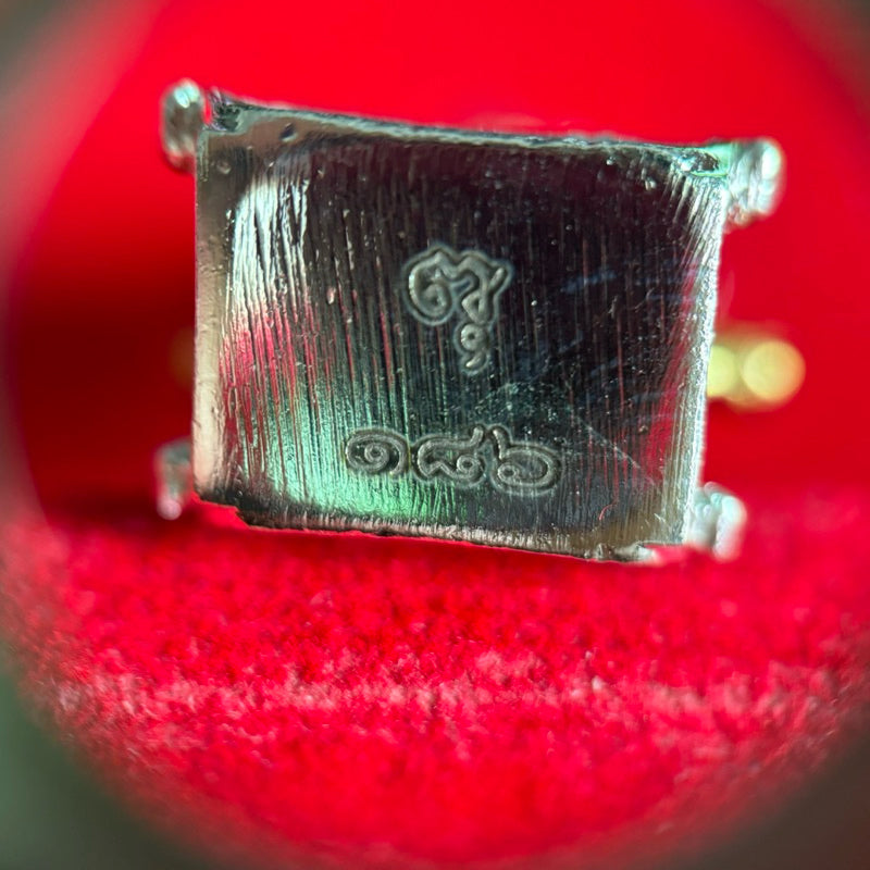 Close-up of Thao Wessuwan collectible amulet with intricate Thai script on metallic surface