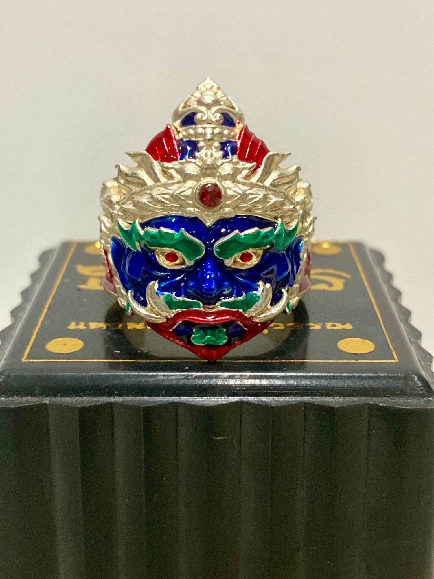 Thao Wessuwan protection ring featuring intricate detailing and vibrant colors, set on a decorative black box