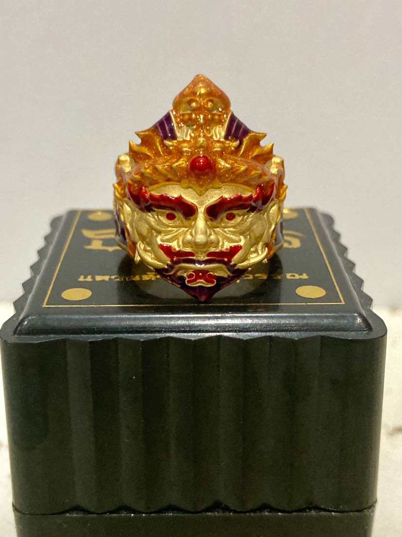 Thao Wessuwan protection ring featuring a detailed golden and red design, displayed on a black decorative box