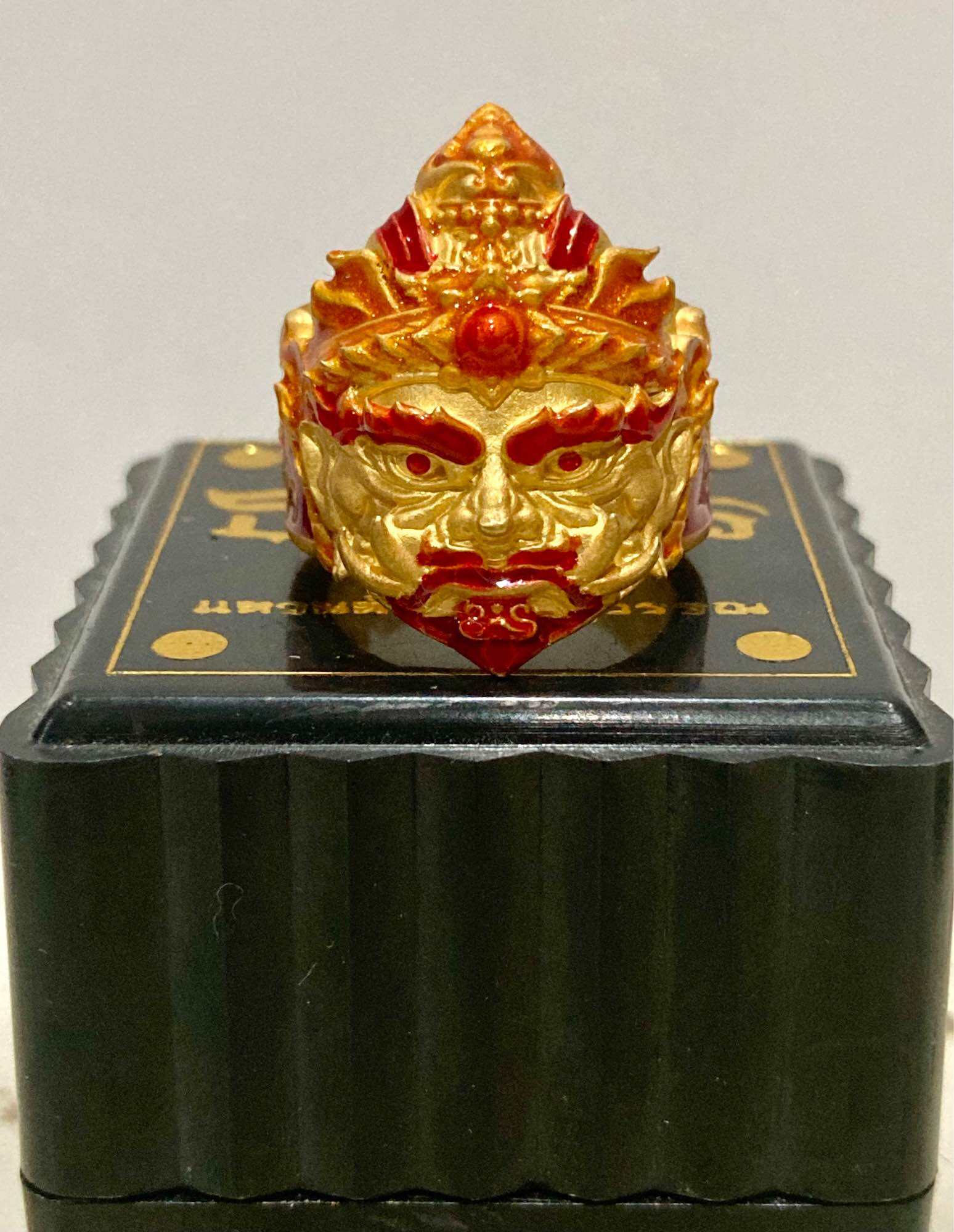 Thao Wessuwan protection ring crafted in gold with intricate detailing and vibrant colors, displayed on a decorative stand