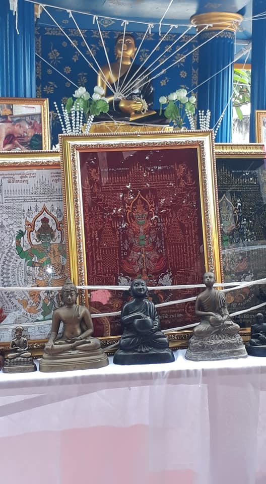 Thao Wessuwan yantra cloth displayed behind ornate Buddha statues in a spiritual setting