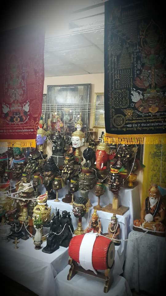 Thao Wessuwan yantra cloth displayed in a shop alongside various traditional Thai sculptures