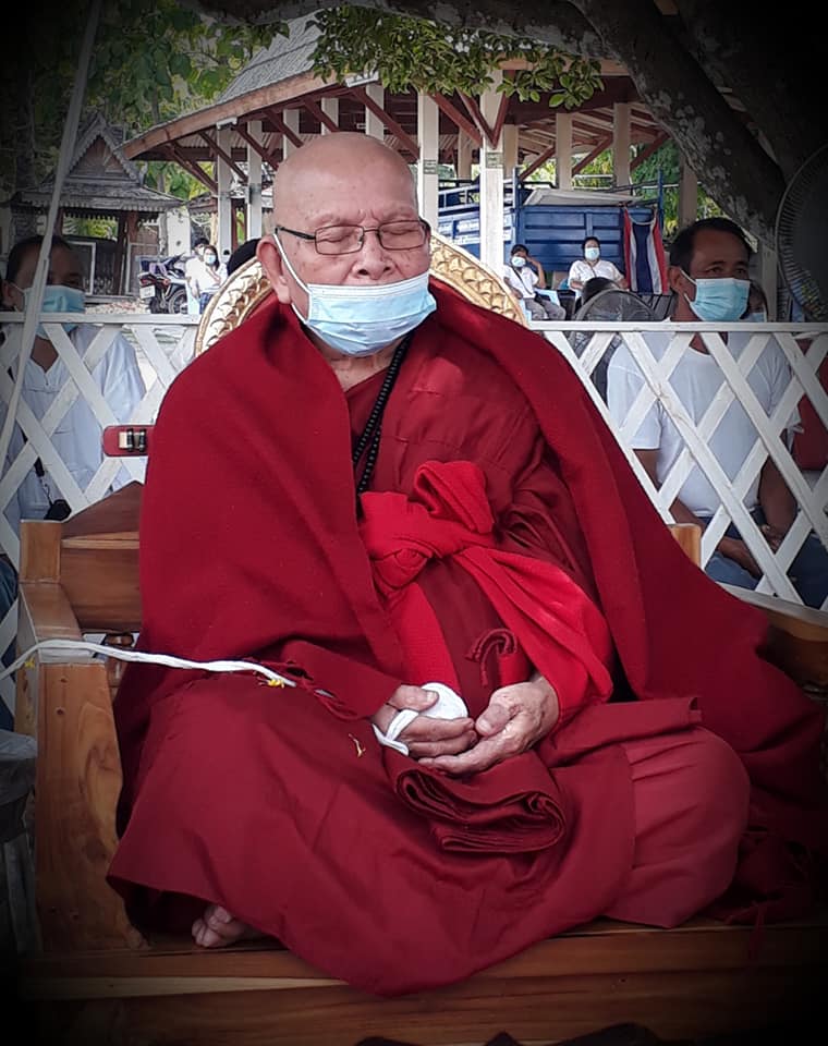 Thao Wessuwan yantra cloth displayed alongside a serene monk in traditional attire