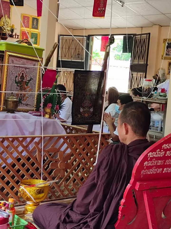 Monk praying with Thao Wessuwan yantra cloth displayed in a serene temple setting
