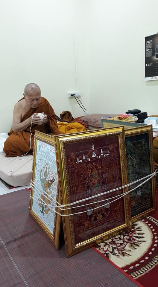 Monk creating Thao Wessuwan yantra cloth with framed designs in a serene environment