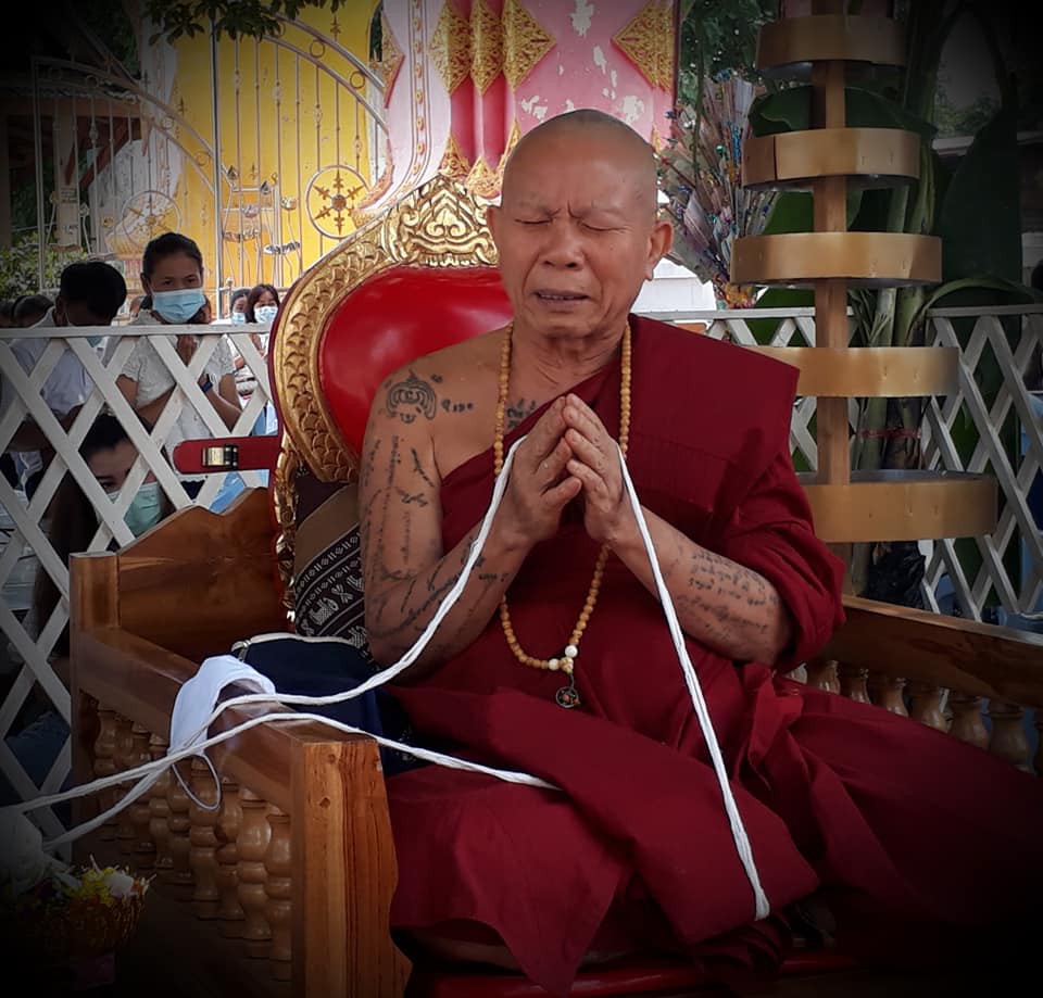 Buddhist monk in meditation with a Thao Wessuwan yantra cloth in traditional setting
