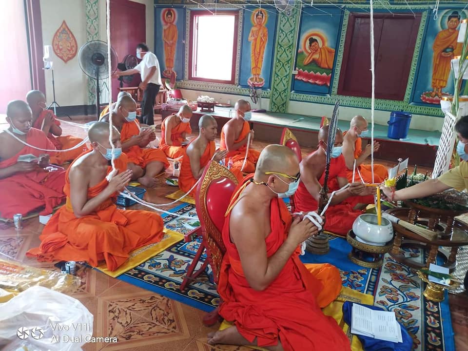 Buddhist monks performing a ceremonial blessing with Thao Wessuwan yantra cloth in a temple setting