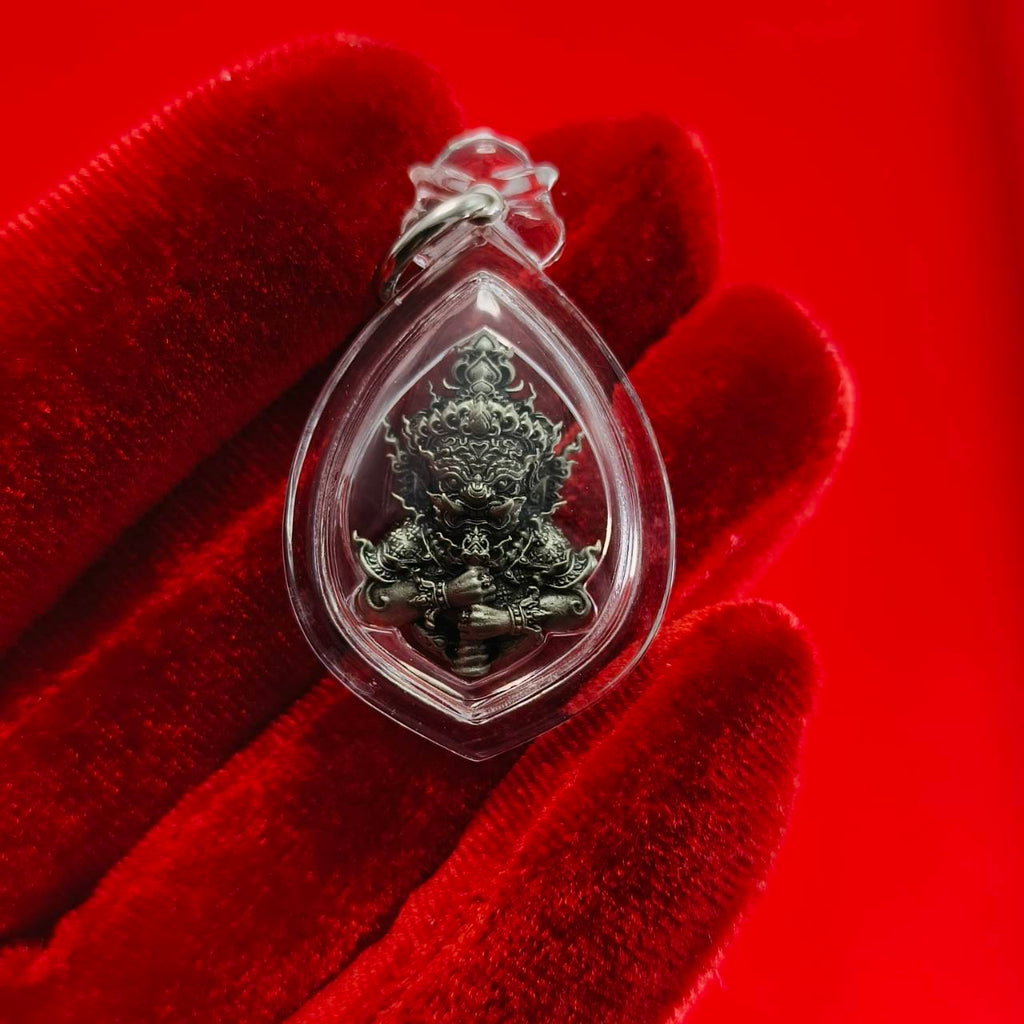 Thao Wessuwanno amulet encased in clear plastic, showcasing intricate details on a red background